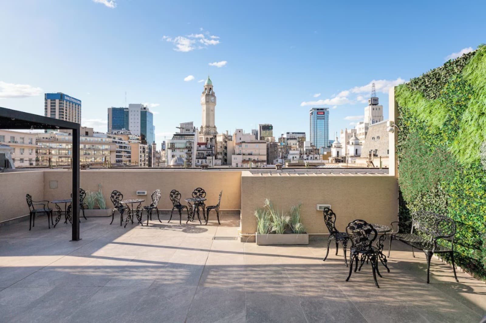 Terraza con mesas de hierro y vista al skyline porteño